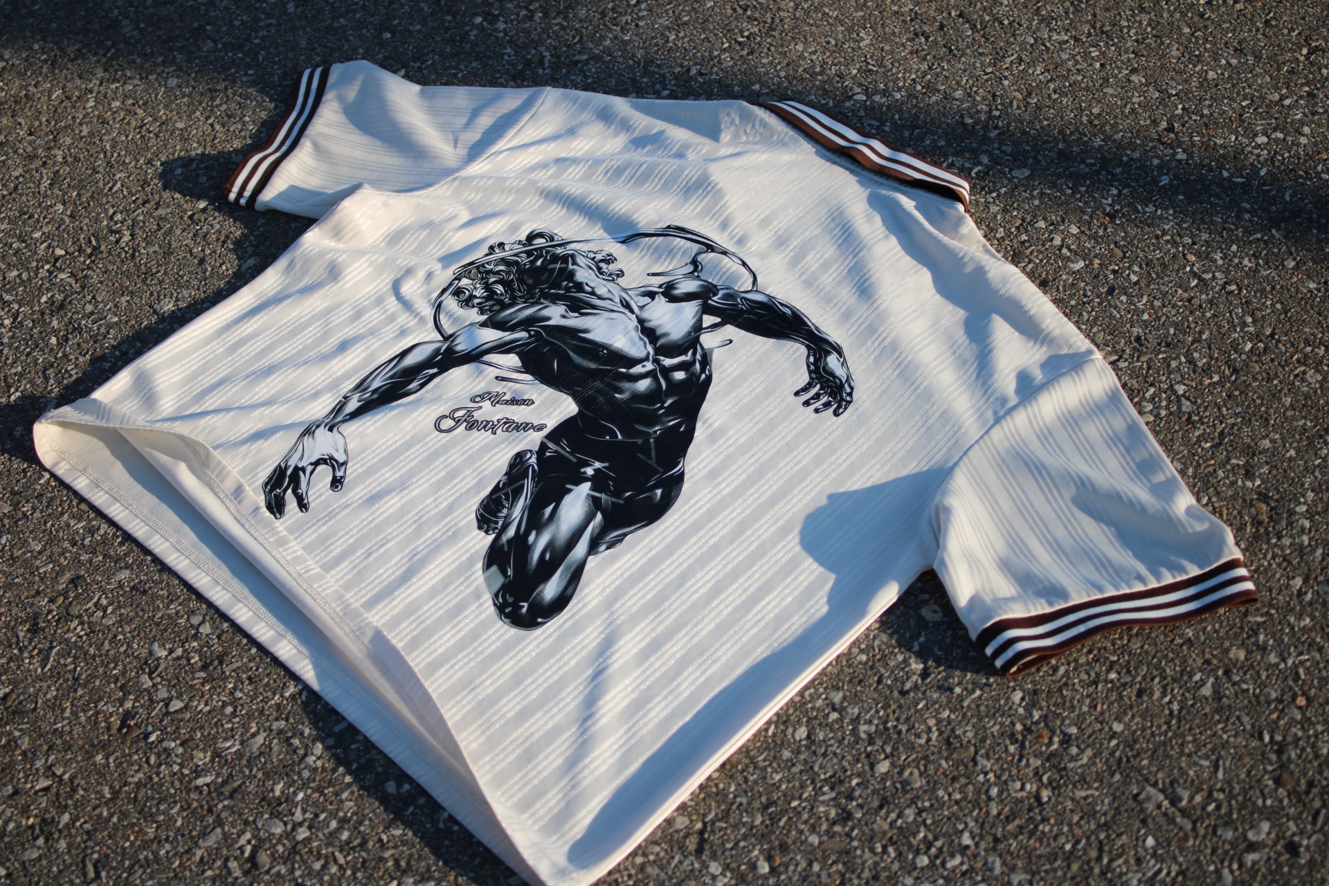 Back view of the Satin Pinstripe Polo showing the contorted figure illustration and Maison Fontane script logo
