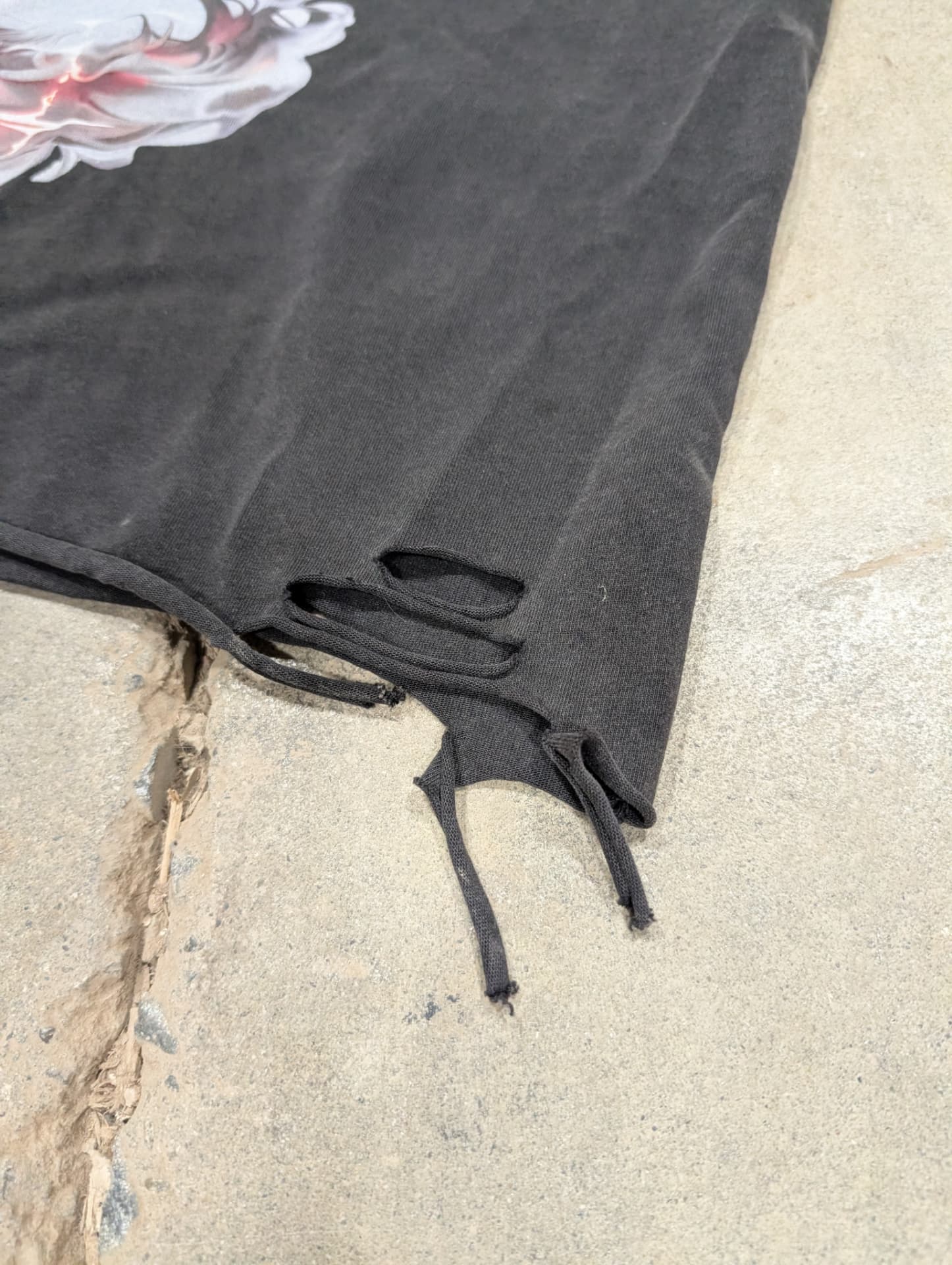 Detail of the shredded raw hem on the Veiled Hand acid wash tee